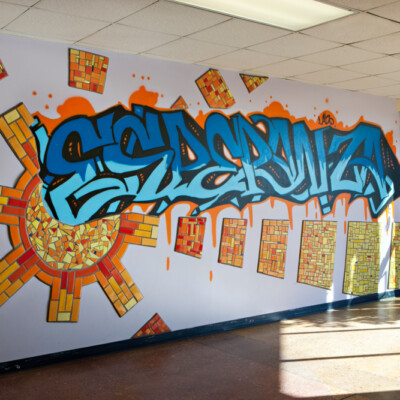 Wall art that says "Esperanza" in blue and orange in the main entrance of La Academia De Esperanza's facility