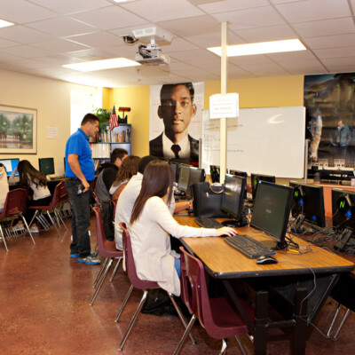 Male teacher teaching computer skills to students