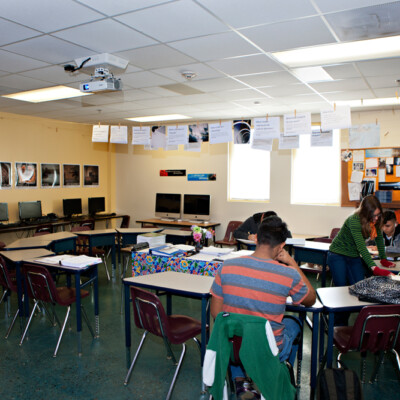 Female teacher helping a group of students at La Academia De Esperanza Charter School in Albuquerque, NM