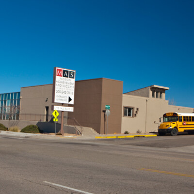 A large brown and beige school building with a sign that says "M.A.S. Mission Achievement and Success"