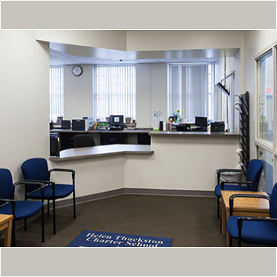 An administrative office with white walls a built in desk and blue chairs