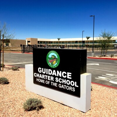 Black and white sign that says "Guidance Charter School Home of The Gators" at the Guidance campus