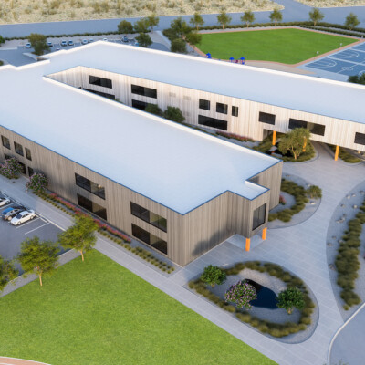 Aerial view of a modern L-shaped office building with parking and landscaped surroundings.